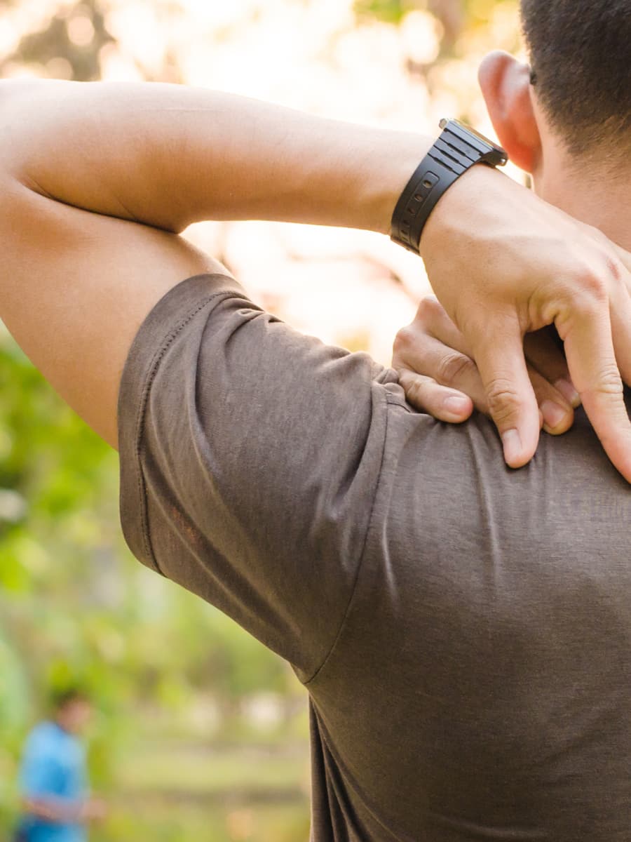 Person outdoors rubbing their shoulder